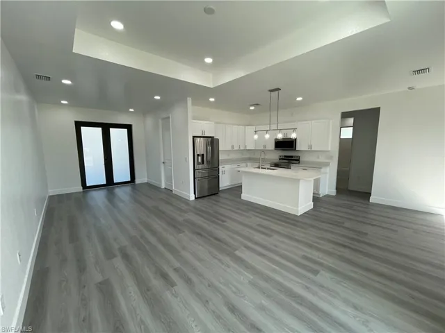 Kitchen featuring sink, light wood-type flooring, an island with sink, appliances with stainless steel finishes, and white cabinetry