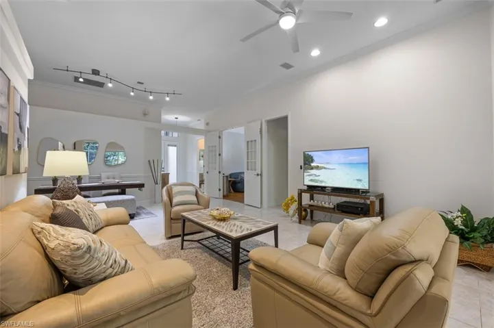 Living room with rail lighting, ceiling fan, ornamental molding, and light tile patterned floors