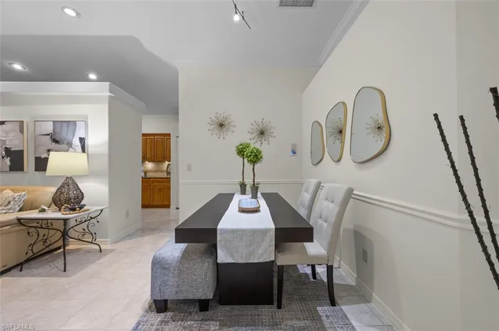 Dining room with light tile patterned flooring, rail lighting, and ornamental molding
