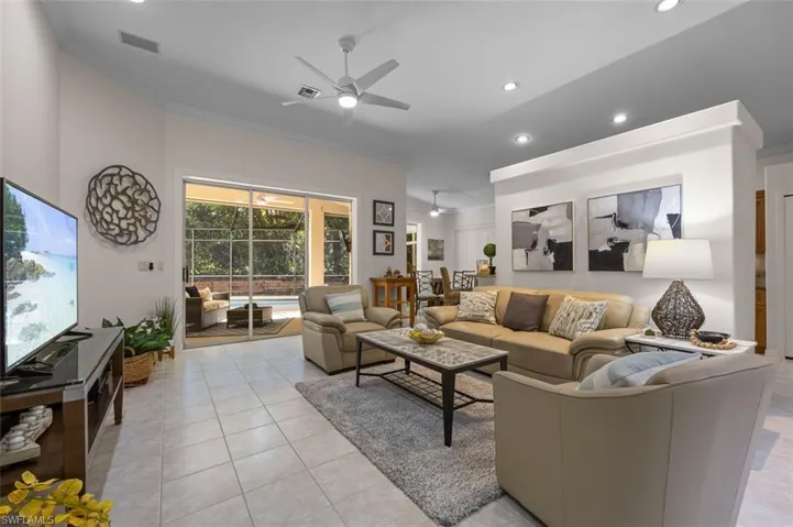 Living room with light tile patterned flooring, ornamental molding, and ceiling fan
