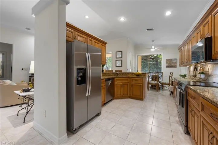 Kitchen with ceiling fan, dark stone countertops, kitchen peninsula, and stainless steel appliances