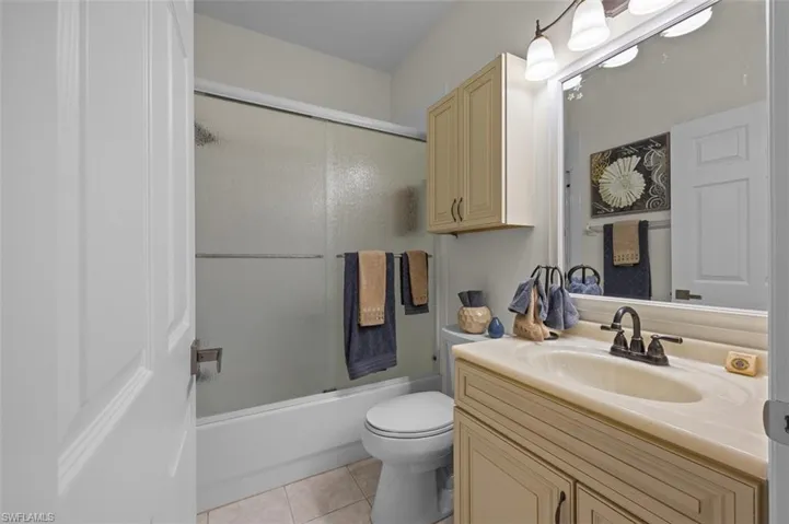 Full bathroom featuring vanity, toilet, shower / bath combination with glass door, and tile patterned floors