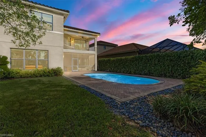 Pool at dusk featuring a patio, ceiling fan, and a yard