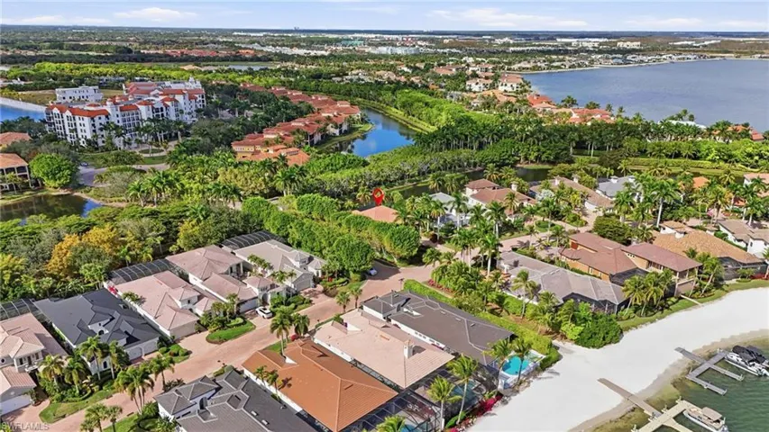 Aerial perspective of suburban area featuring a nearby body of water and a tree filled landscape