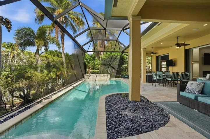 View of swimming pool featuring a patio, a sunroom, outdoor dining area, glass enclosure, and a pool with connected hot tub