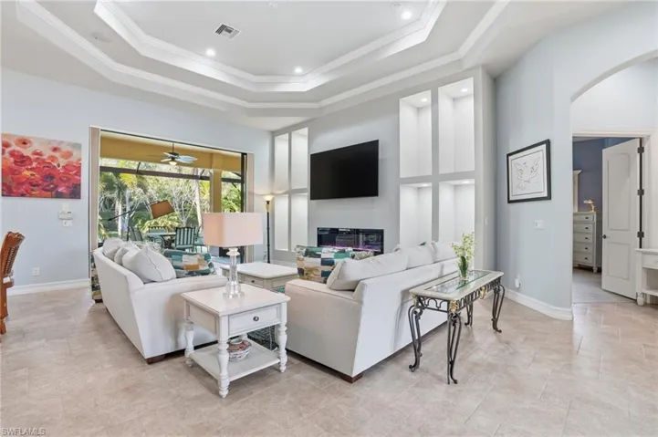 Living area featuring arched walkways, crown molding, a high ceiling, a raised ceiling, and ceiling fan