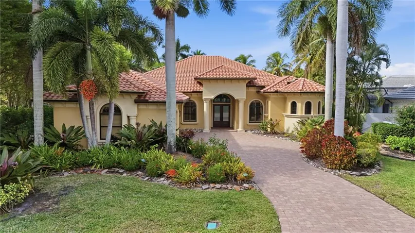 Mediterranean / spanish house with stucco siding, french doors, decorative driveway, a tiled roof, and a front lawn