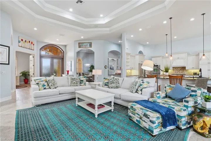 Living area with a raised ceiling, recessed lighting, ornamental molding, and a high ceiling