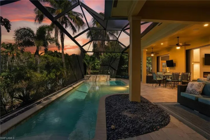 Pool at dusk with a patio area, a sunroom, outdoor dining space, and a lanai
