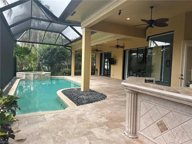 Relaxing pool / spa featuring a patio area, a sunroom, and glass enclosure