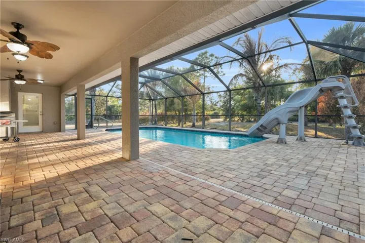 Outdoor pool featuring a patio, a sunroom, glass enclosure, and a water slide