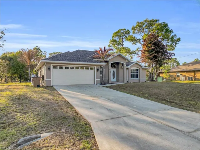 Ranch-style home with a front lawn, concrete driveway, an attached garage, stucco siding, and roof with shingles