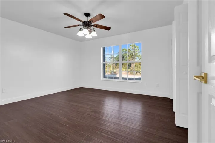 Empty room featuring dark wood-style flooring and a ceiling fan