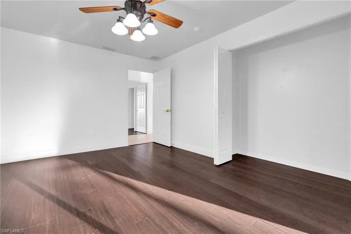 Unfurnished room featuring ceiling fan and dark wood-style floors