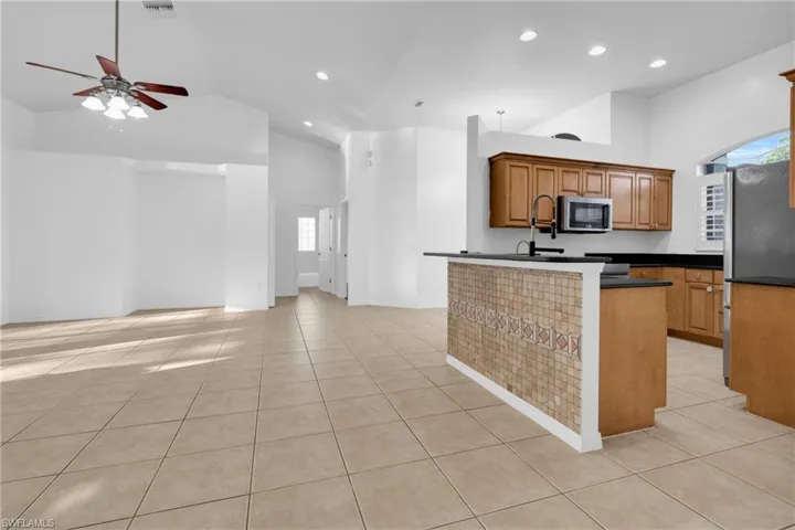 Kitchen featuring wood finish cabinetry, vaulted ceiling, stainless steel appliances, a ceiling fan, and recessed lighting