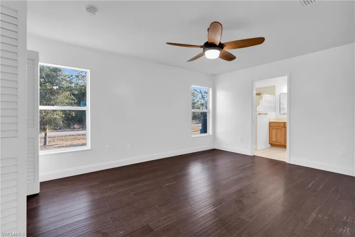 Unfurnished bedroom with hardwood / wood-style floors, ceiling fan, and connected bathroom