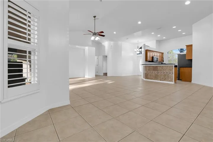 Unfurnished living room with light tile patterned flooring, suspended lighting, ceiling fan, and lofted ceiling
