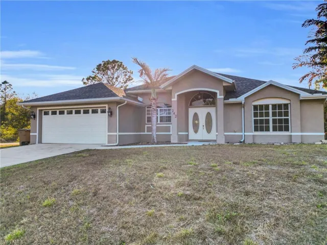 Ranch-style home with stucco siding, a front yard, concrete driveway, a garage, and a shingled roof