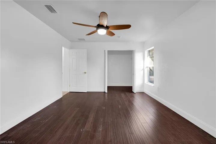 Unfurnished bedroom featuring dark wood-style flooring, a closet, and a ceiling fan
