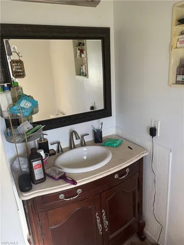 Vanity featuring a stone countertop with an integrated oval basin, dark wood-finish cabinetry with decorative hardware, and a framed wall mirror