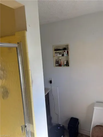 Recessed wall-mounted shelving unit and shower enclosure featuring yellow wall tile and metal frame