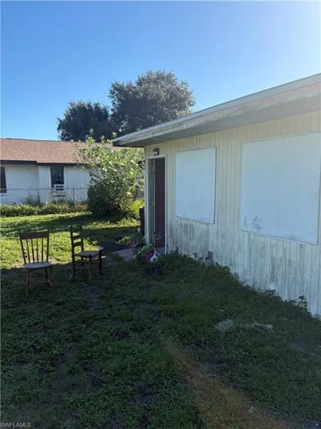 Exterior elevation featuring vertical siding, covered doorway, and window boarding