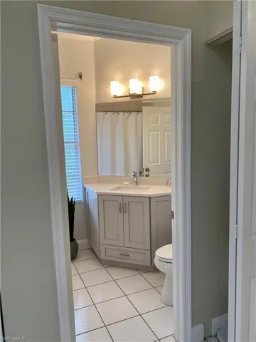 Bathroom featuring toilet, vanity, tile patterned floors, and curtained shower