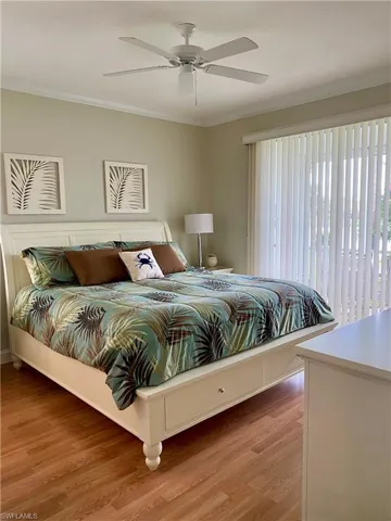 Bedroom featuring ceiling fan, light hardwood / wood-style floors, and crown molding
