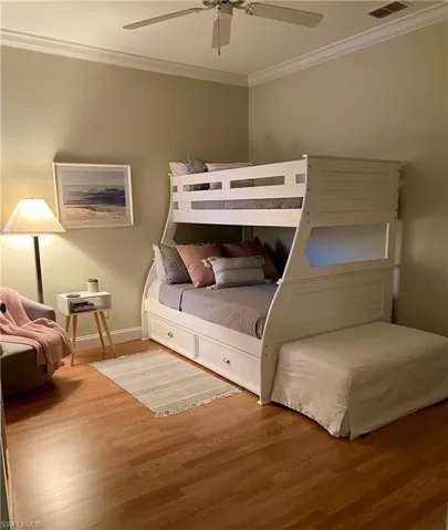 Bedroom with ceiling fan, crown molding, and wood-type flooring