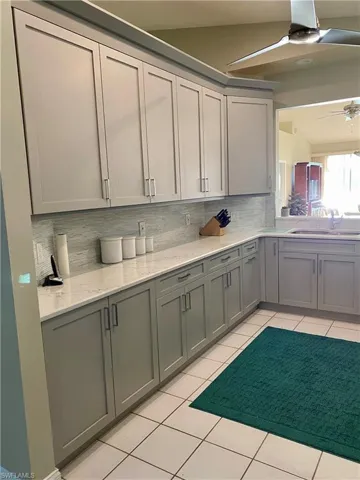 Kitchen with ceiling fan, gray cabinets, sink, and backsplash