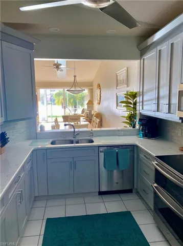 Kitchen with tasteful backsplash, stainless steel appliances, ceiling fan, sink, and light tile patterned flooring