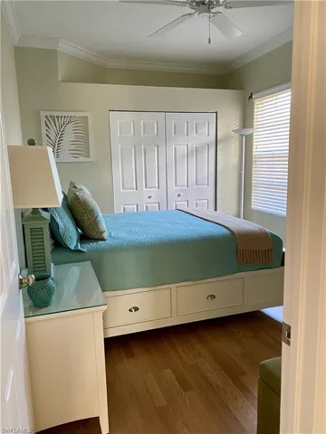 Bedroom featuring a closet, ceiling fan, crown molding, and wood-type flooring