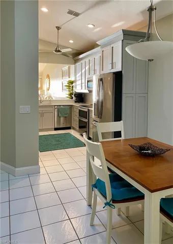 Kitchen with white cabinets, ceiling fan, light tile patterned floors, appliances with stainless steel finishes, and decorative light fixtures