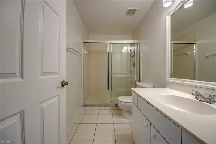 Bathroom featuring tile floors, vanity with extensive cabinet space, a shower with shower door, and toilet