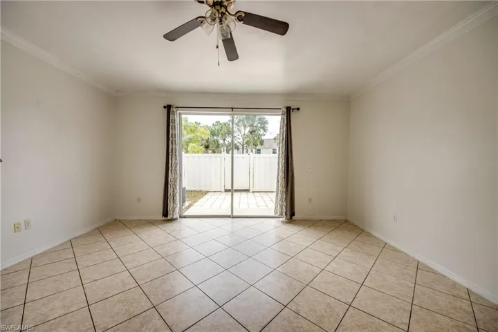 Empty room featuring crown molding, light tile flooring, and ceiling fan