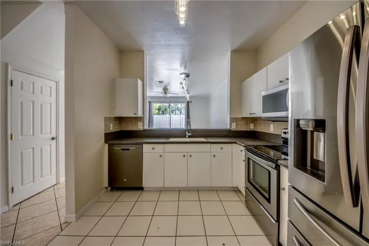 Kitchen featuring appliances with stainless steel finishes, sink, tasteful backsplash, and light tile floors
