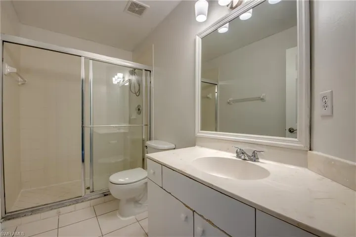 Bathroom featuring walk in shower, tile flooring, toilet, and large vanity