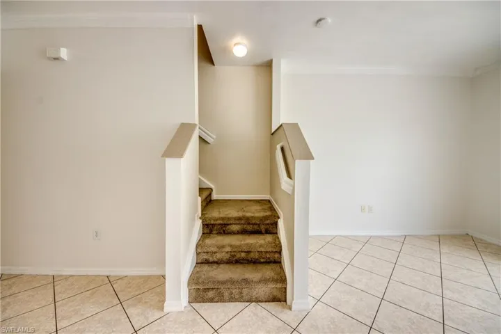 Stairs with ornamental molding and light tile flooring
