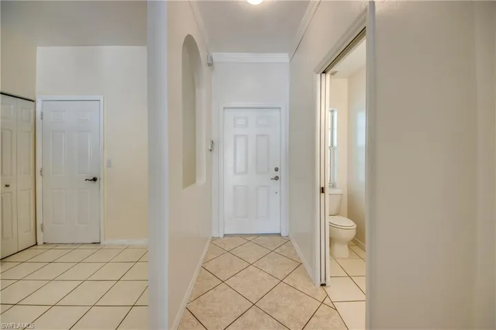 Corridor with light tile flooring and crown molding