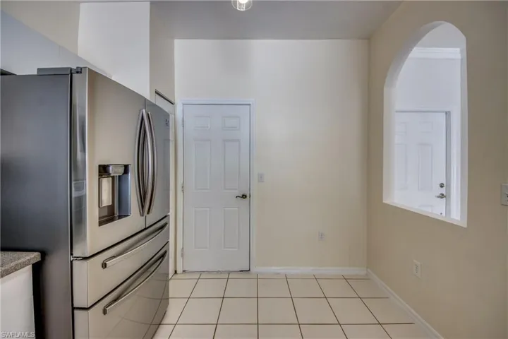 Kitchen with light tile flooring and stainless steel refrigerator with ice dispenser