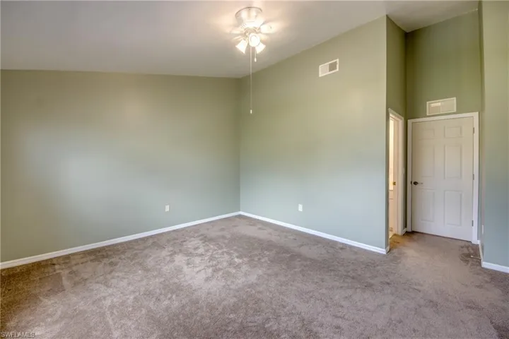 Empty room featuring carpet, ceiling fan, and high vaulted ceiling