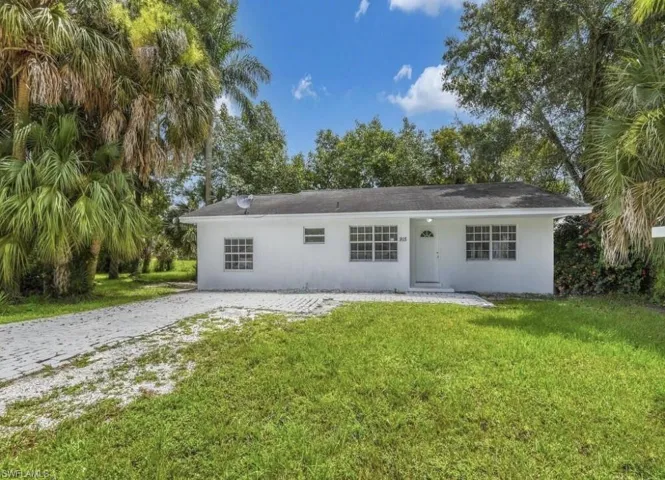 Ranch-style house with stucco siding, a front lawn, driveway, and a patio area