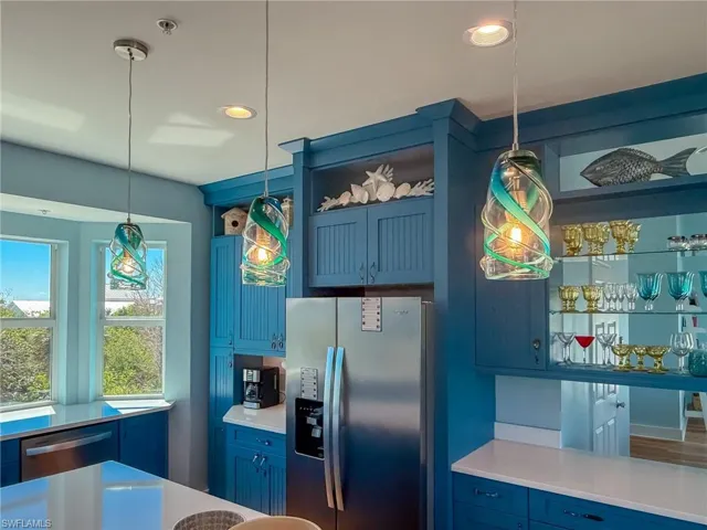 Kitchen with light countertops, blue cabinetry, appliances with stainless steel finishes, and pendant lighting