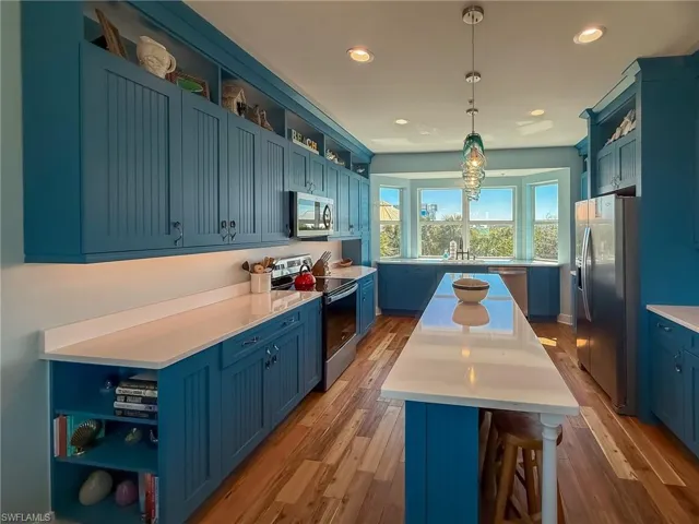 Kitchen with open shelves, blue cabinetry, appliances with stainless steel finishes, and a kitchen island