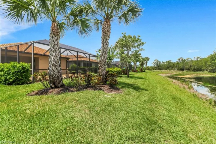 View of green lawn featuring a water view and glass enclosure