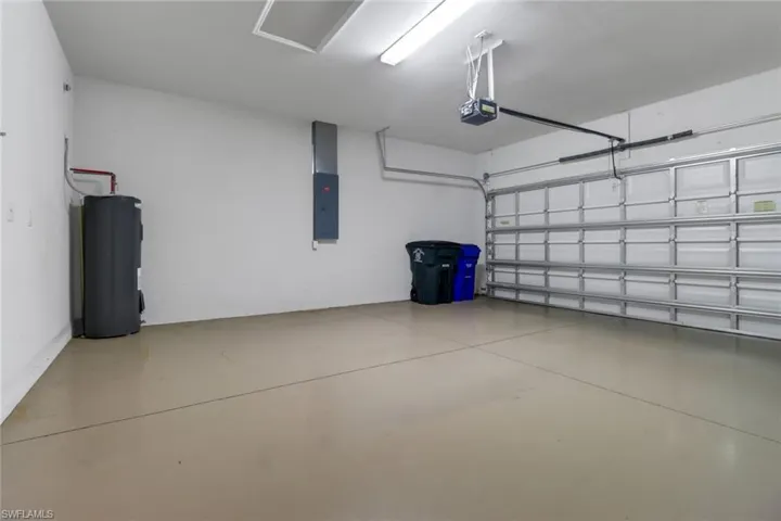 Garage featuring electric water heater, a garage door opener, and electric panel