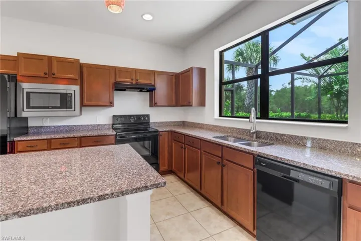 Kitchen featuring black appliances, under cabinet range hood, light tile patterned flooring, brown cabinetry, and recessed lighting