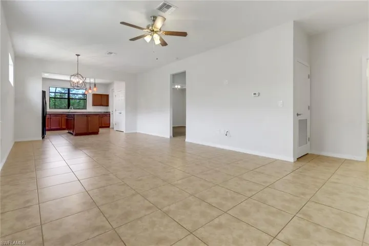 Unfurnished living room with a chandelier, light tile patterned flooring, and ceiling fan