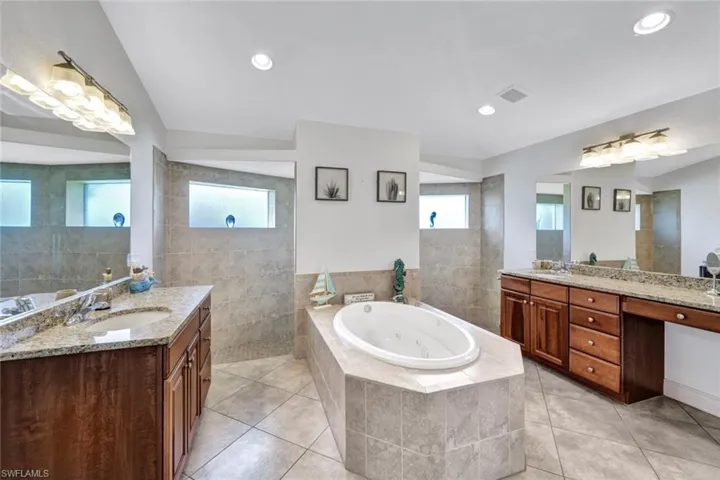 Bathroom featuring a healthy amount of sunlight, tiled bath, tile flooring, and vanity