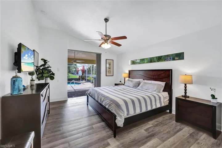 Bedroom featuring access to exterior, ceiling fan, vaulted ceiling, and dark hardwood / wood-style flooring